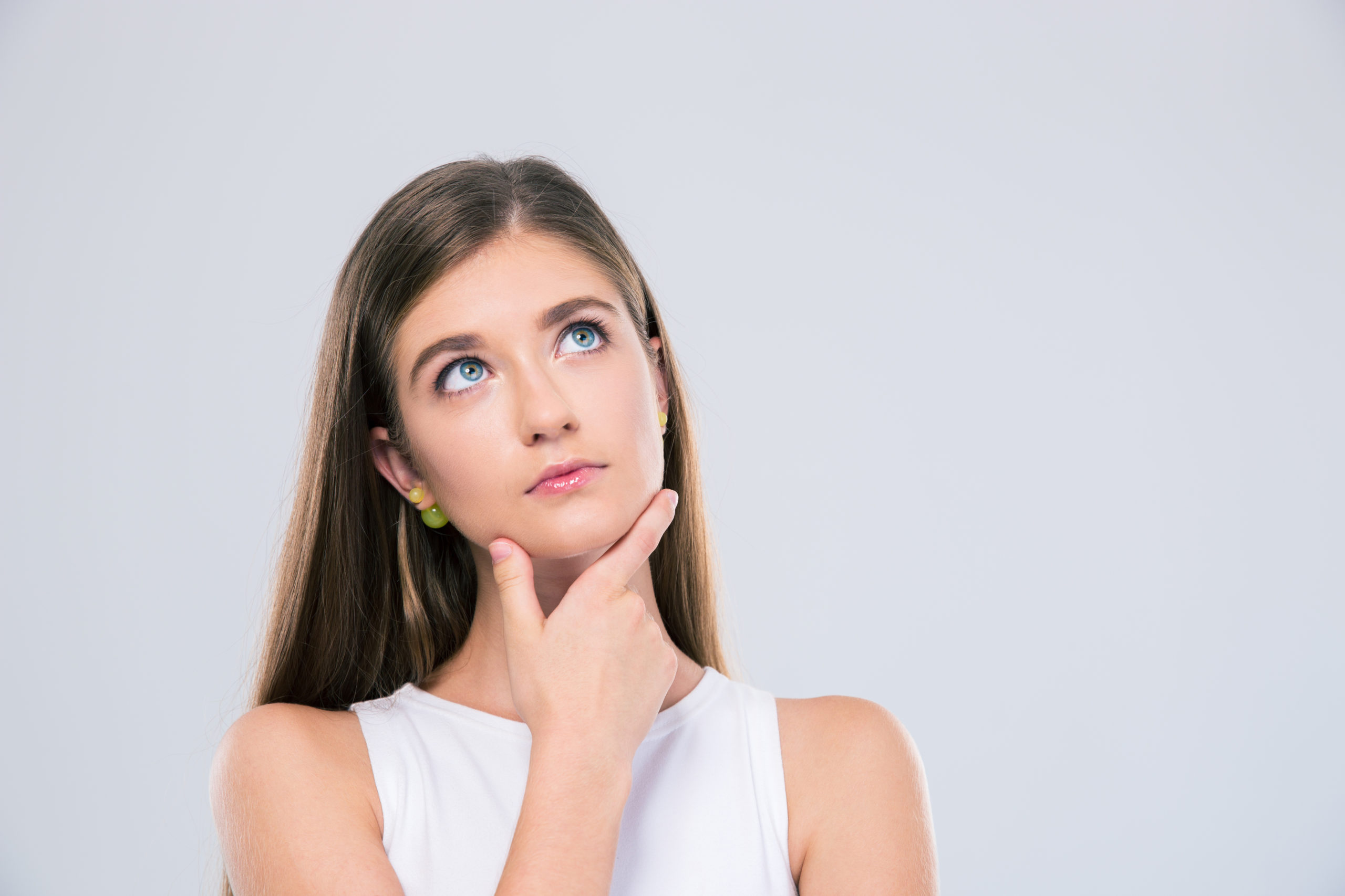 Portrait of a pensive female teenager looking up isolated on a white background